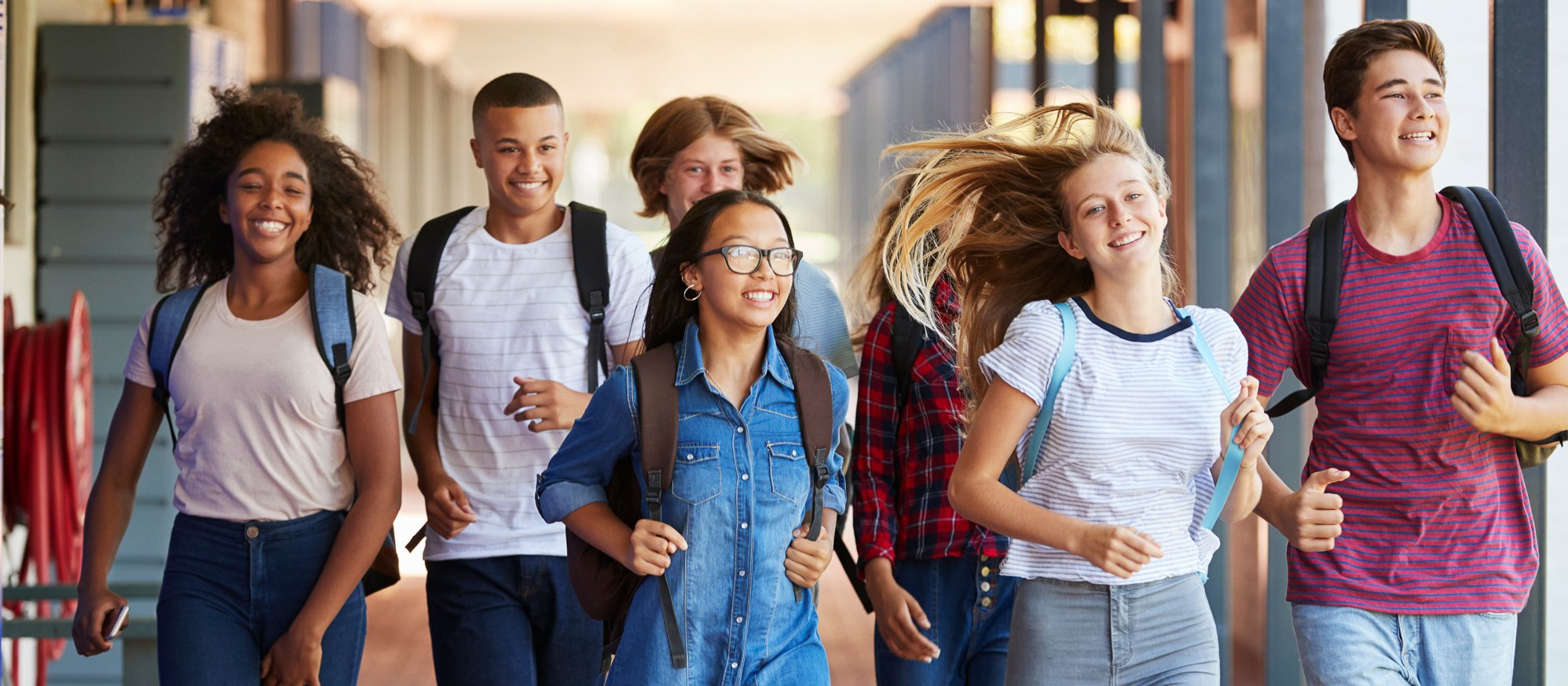 Eine Gruppe fröhlicher Jugendlicher läuft gemeinsam Richtung Schule.