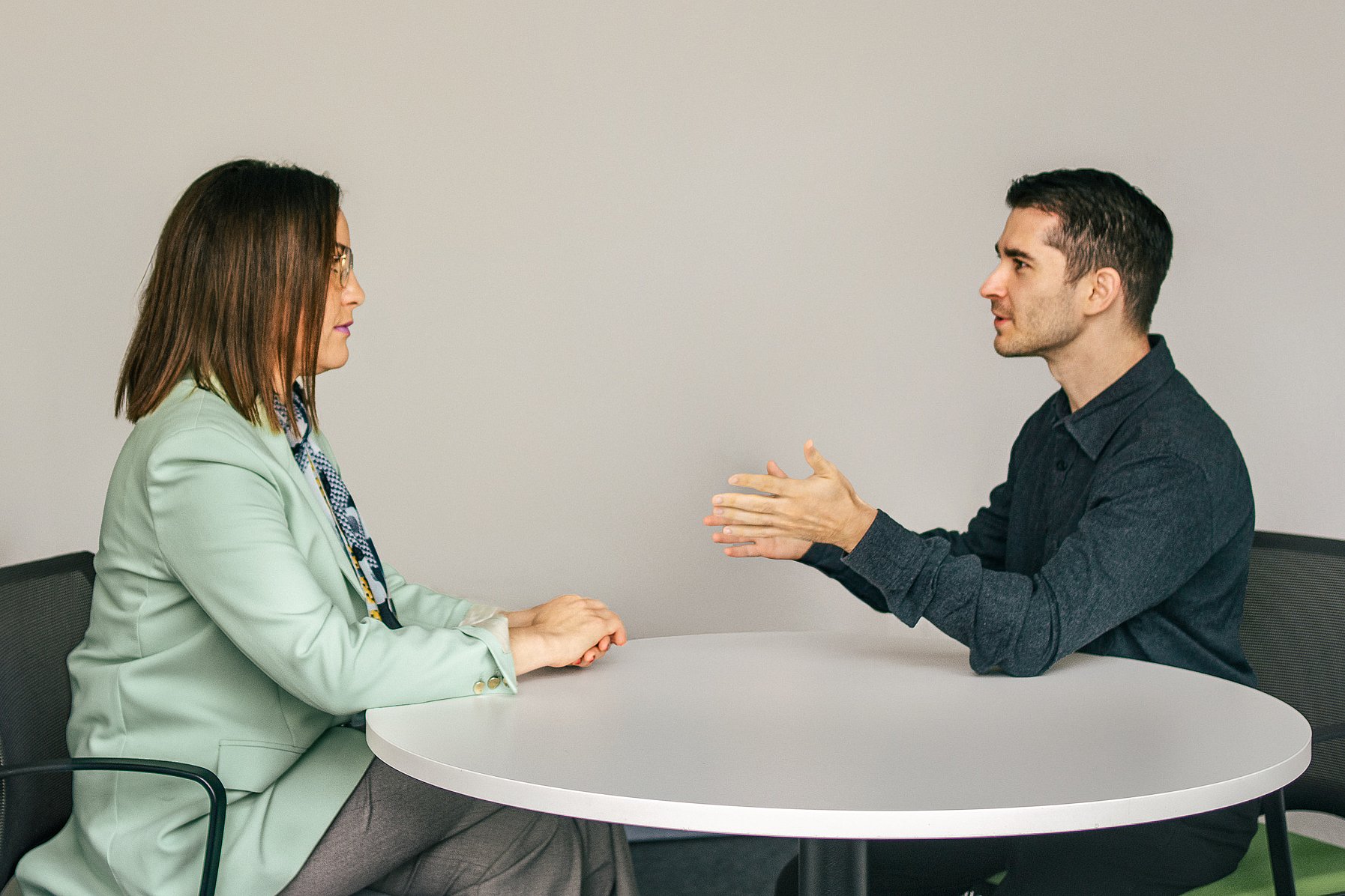 Eine Frau und Vincenzo Rocco sitzen sich an einem runden Tisch gegenüber und führen ein konzentriertes coaching Gespräch