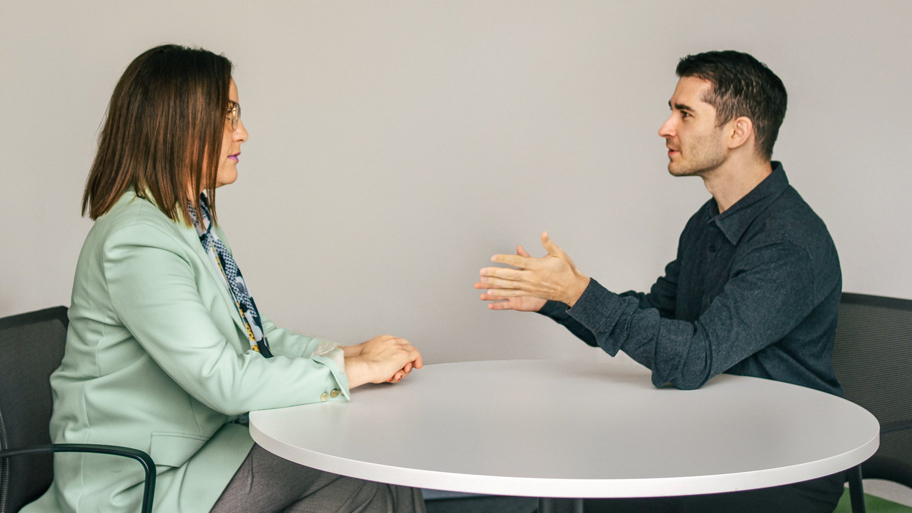 Eine Frau und Vincenzo Rocco sitzen sich an einem runden Tisch gegenüber und führen ein konzentriertes coaching Gespräch