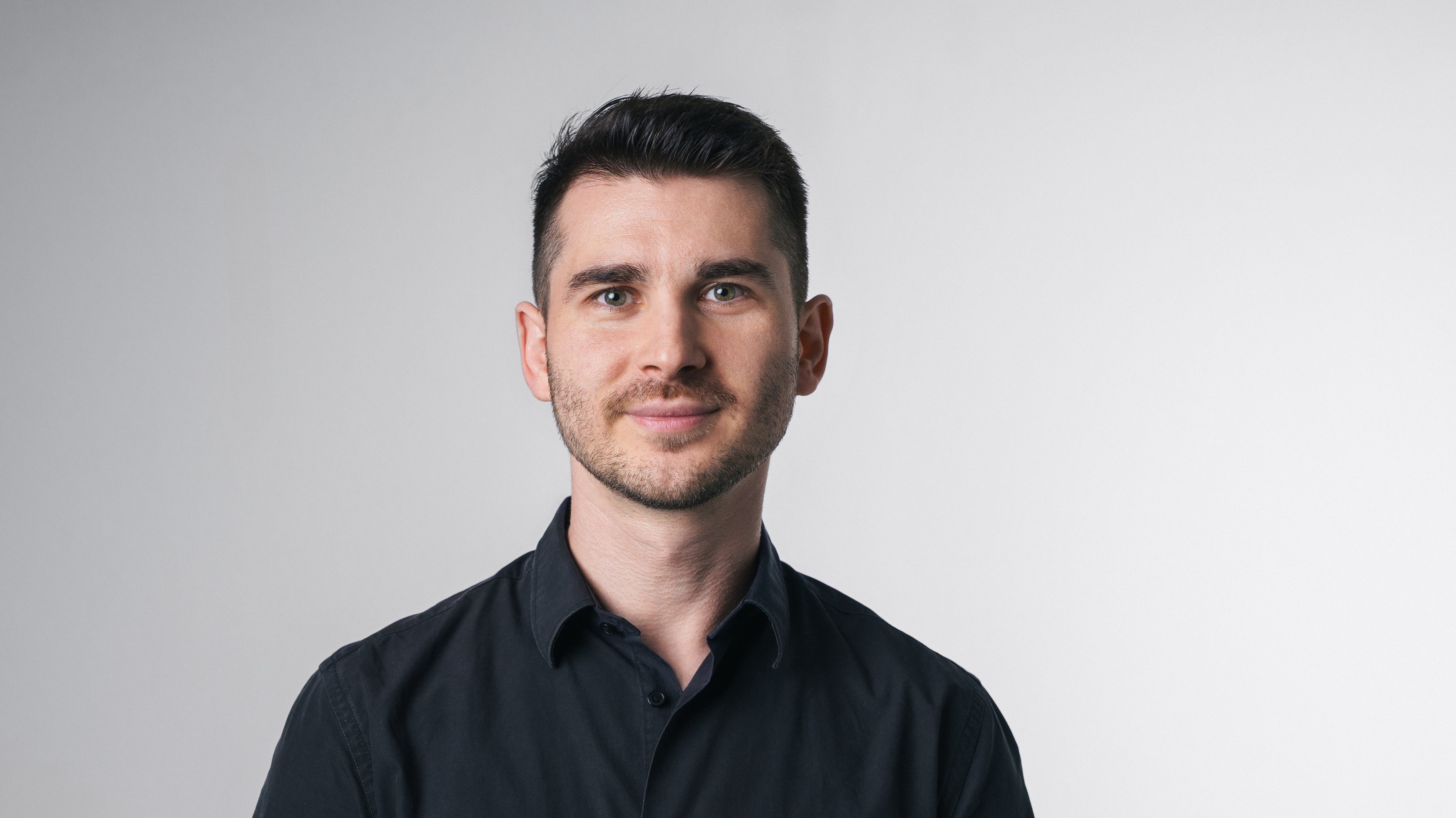 Vincenzo Rocco steht vor einem hellen Hintergrund und blickt direkt in die Kamera